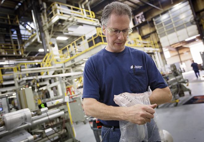Person wearing safety goggles working in a large, industrial  facility.